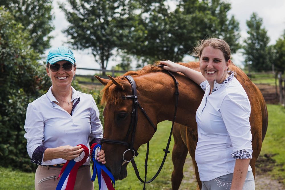 Show horses and handlers pose with award ribbons in a sunny field.
