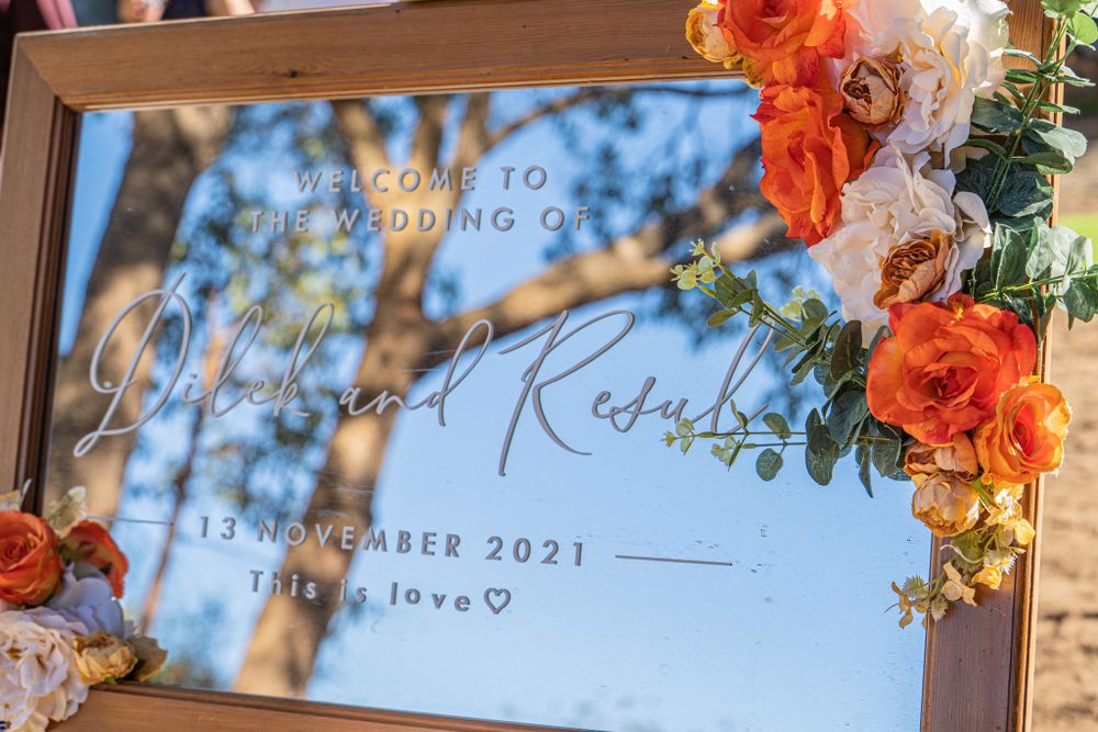 Wedding invitation with orange flowers in wooden frame displaying date and names.