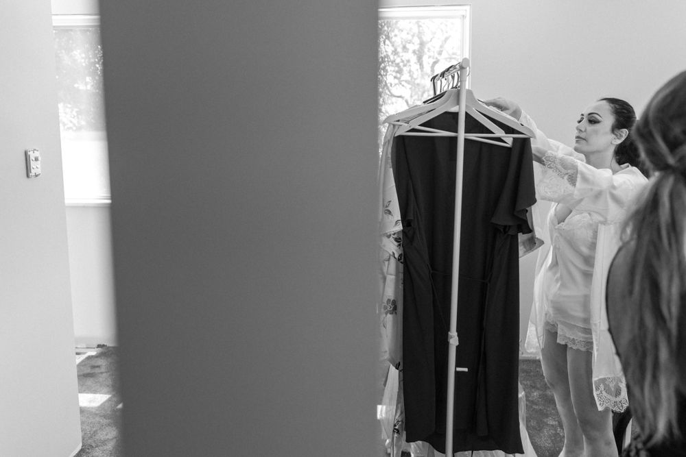 A black and white getting ready scene with clothing hanging on a rack.