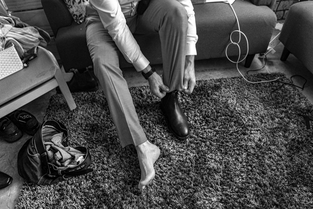 Black and white photo of formal shoes and feet being put on during preparation.