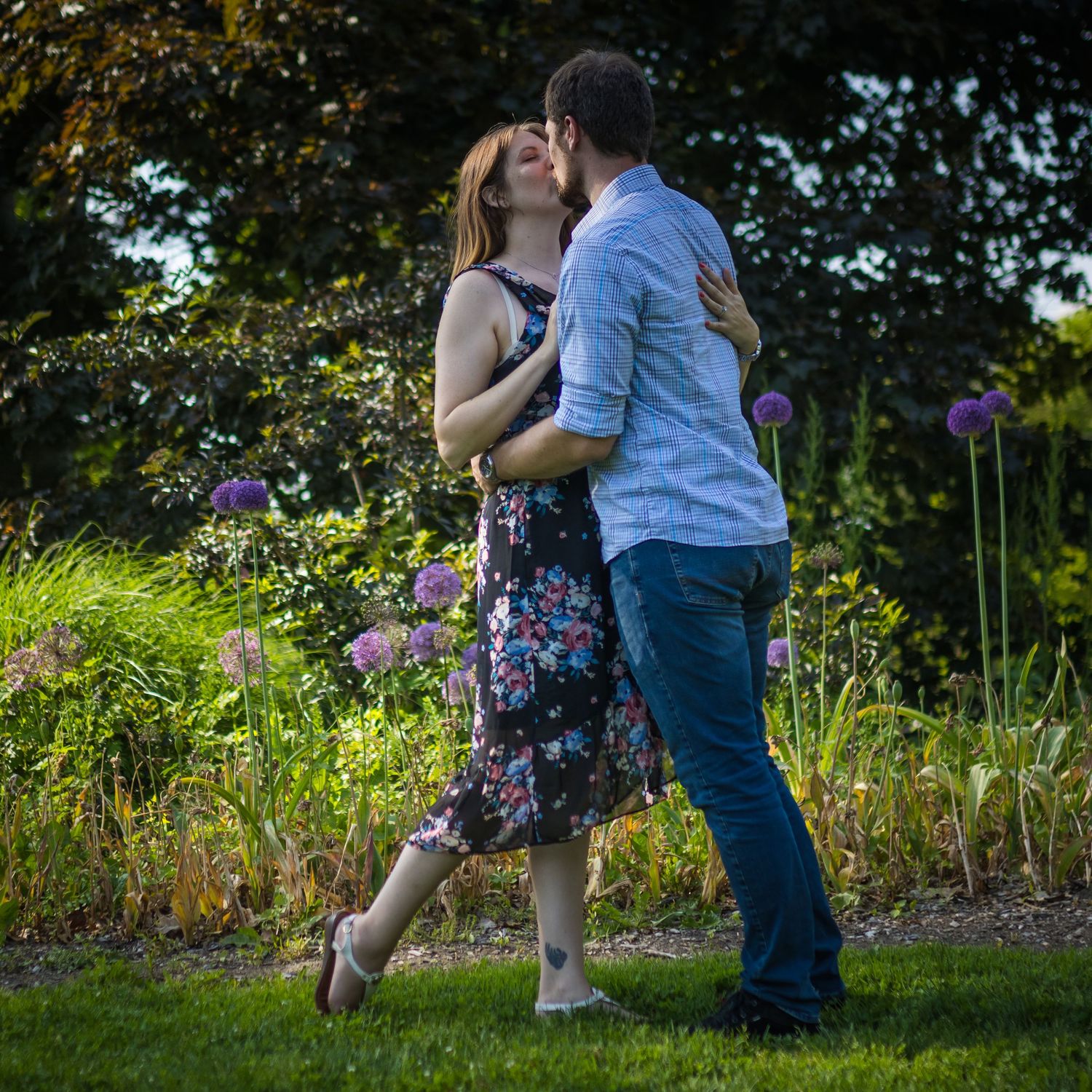 Couple dancing together in a garden with purple flowers blooming.