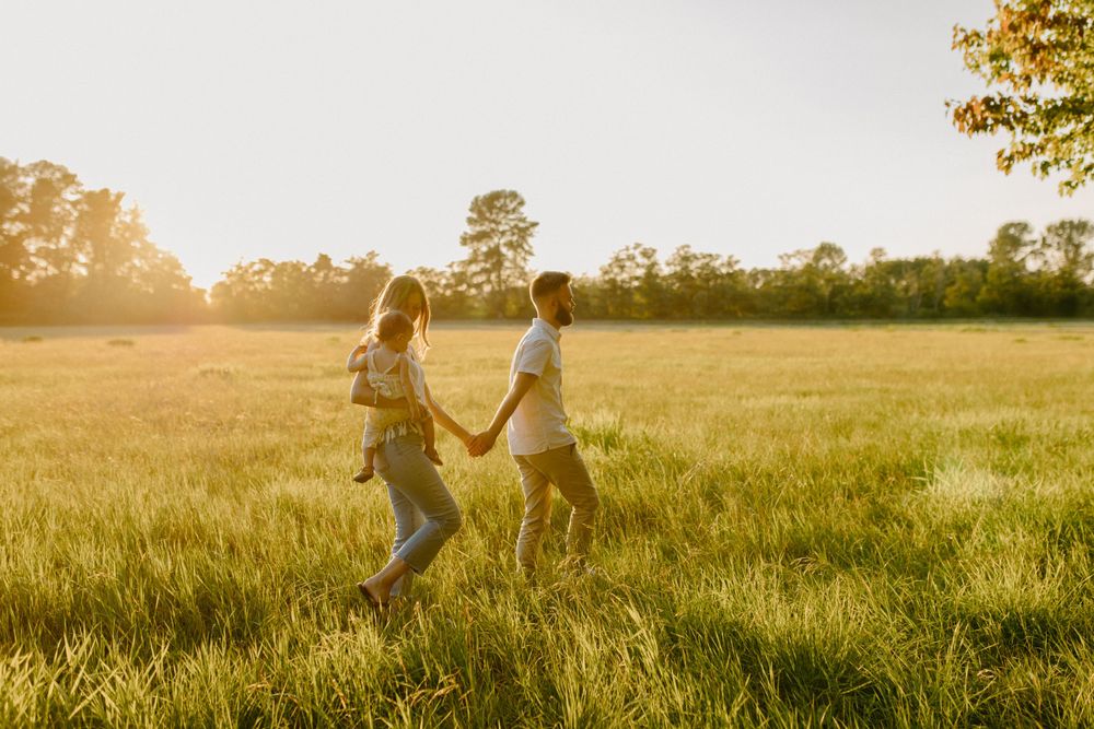 Two people running hand in hand through a sun-drenched meadow.