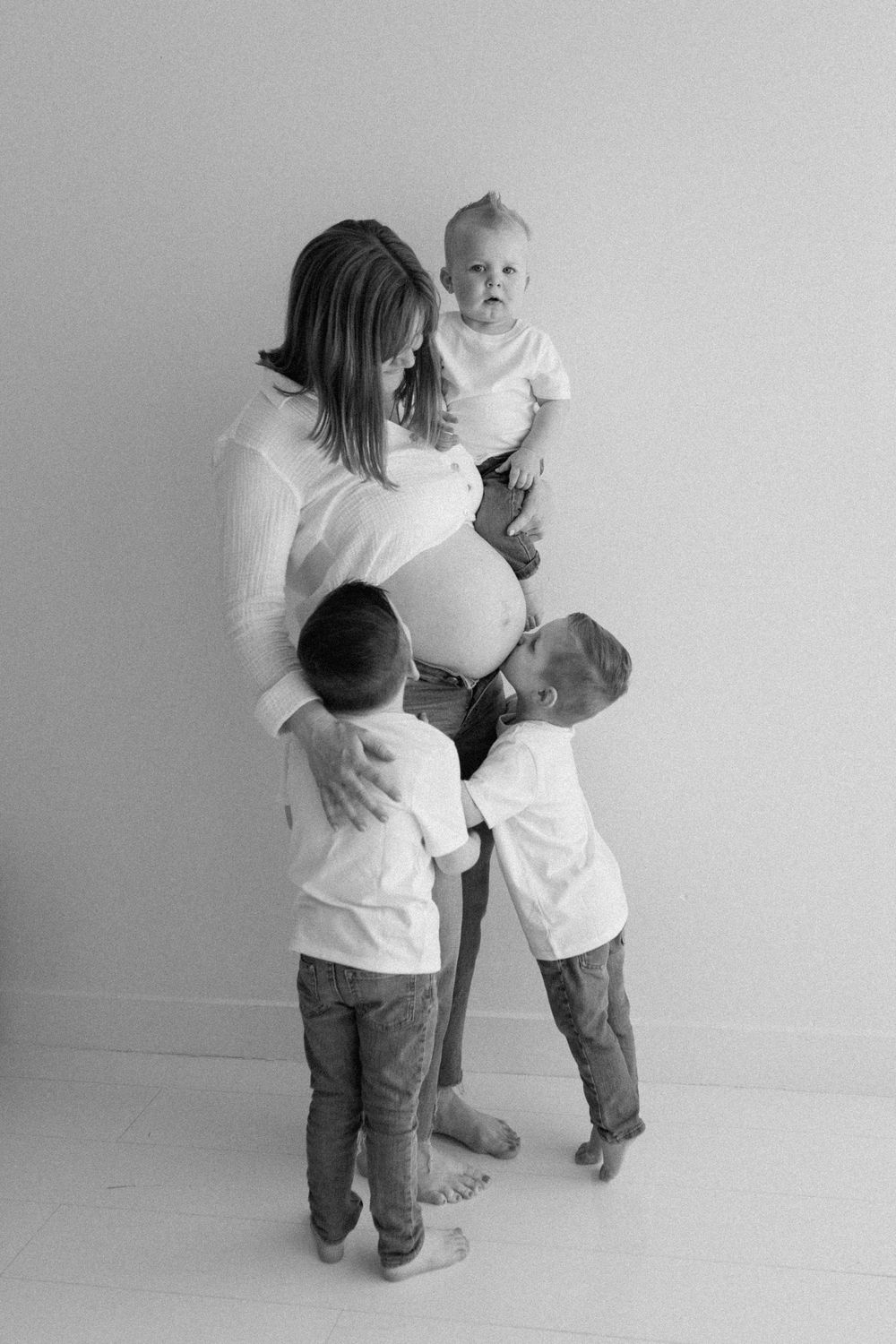 Black and white series showing two toddlers in white shirts and jeans playfully interacting with a balloon together.
