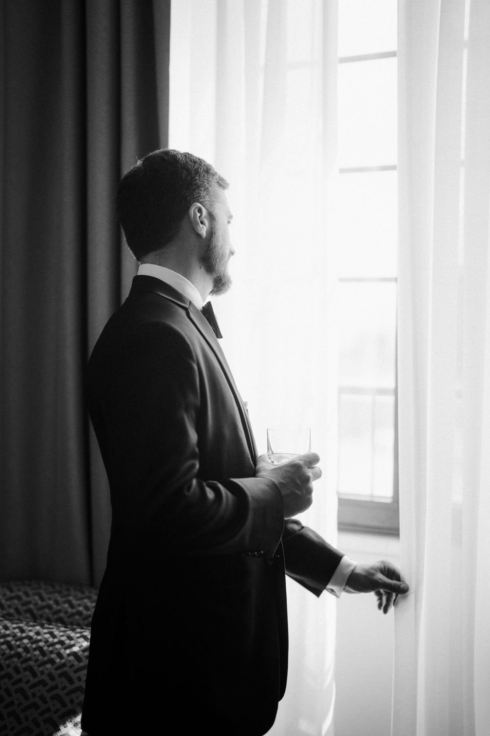 Silhouette of person in formal attire standing by window with curtains. Photoshoot by Venice Photographer Alina Indi