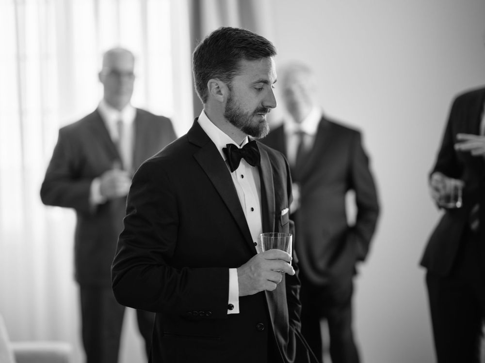 Wedding party members in black suits socialize during celebration. Photoshoot by Venice Photographer Alina Indi