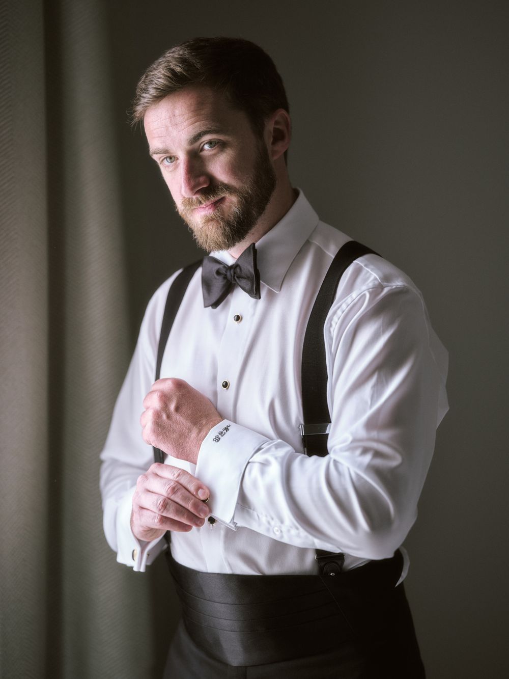 Formal portrait of person adjusting cufflinks while wearing suspenders and bow tie. Photoshoot by Venice Photographer Alina Indi