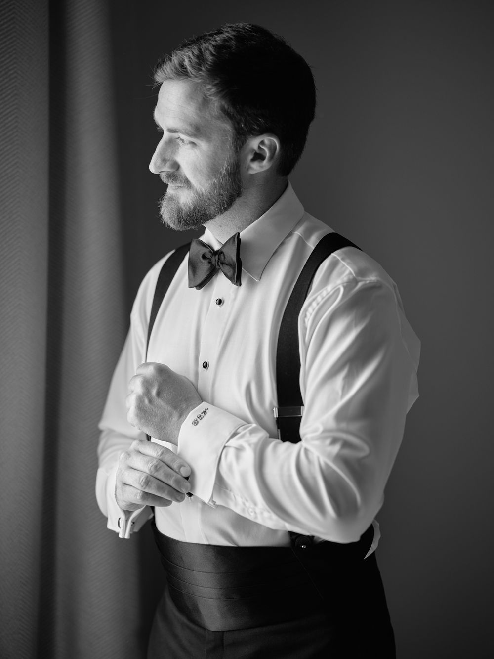 Black and white photo showing a person adjusting their suspenders while wearing a white dress shirt. Photoshoot by Venice Photographer Alina