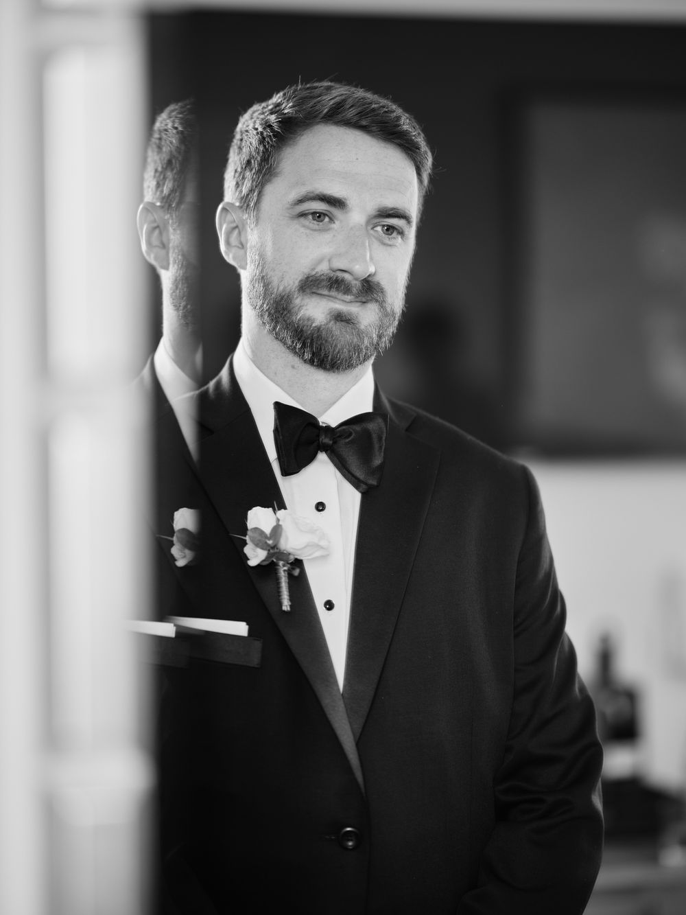 Man in formal black tuxedo and bowtie smiling in black and white portrait. Photoshoot by Venice Photographer Alina Indi
