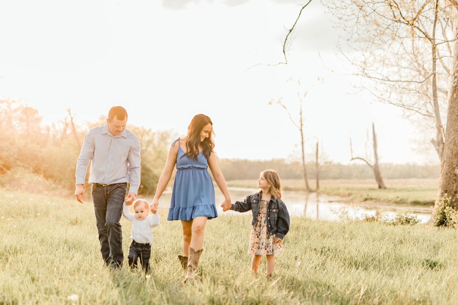 Family walking together through sunlit field during golden hour.