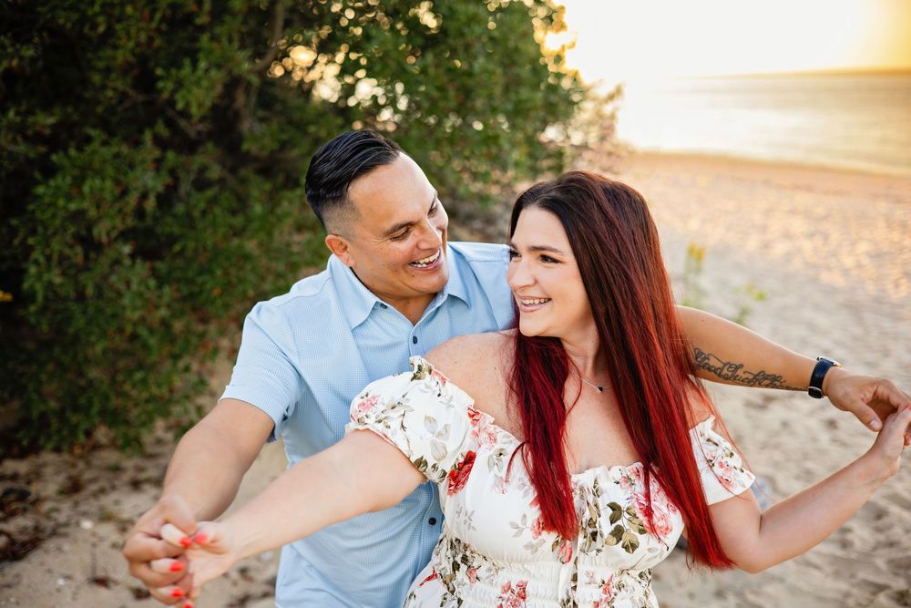 A couple in coordinated outfits share romantic moments during a golden hour photoshoot in a park setting.