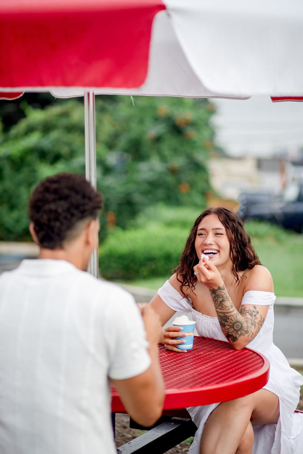 A joyful moment shared between a couple enjoying treats at an outdoor table.