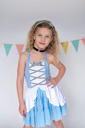 A blue and white dress with corset-style lacing detail and tiered skirt photographed against a backdrop with pastel bunting.