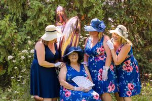 Group of women in coordinated blue dresses sharing laughs in garden setting.
