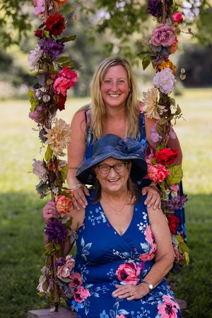 Two people share joyful moment on floral swing decorated with vibrant blooms.