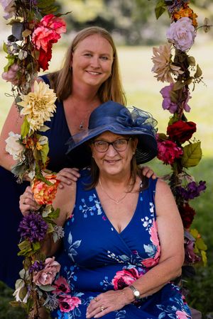 A floral swing decorated with colorful blooms creates a charming outdoor portrait setting with blue floral dresses.