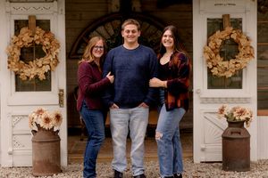 Autumn portrait in front of white doors decorated with golden wreaths and rustic planters.