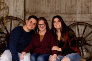 Family portrait with rustic wooden wagon wheels and barn wood background.