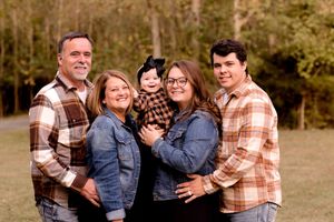 Happy family group portrait outdoors with matching casual outfits in autumn setting.