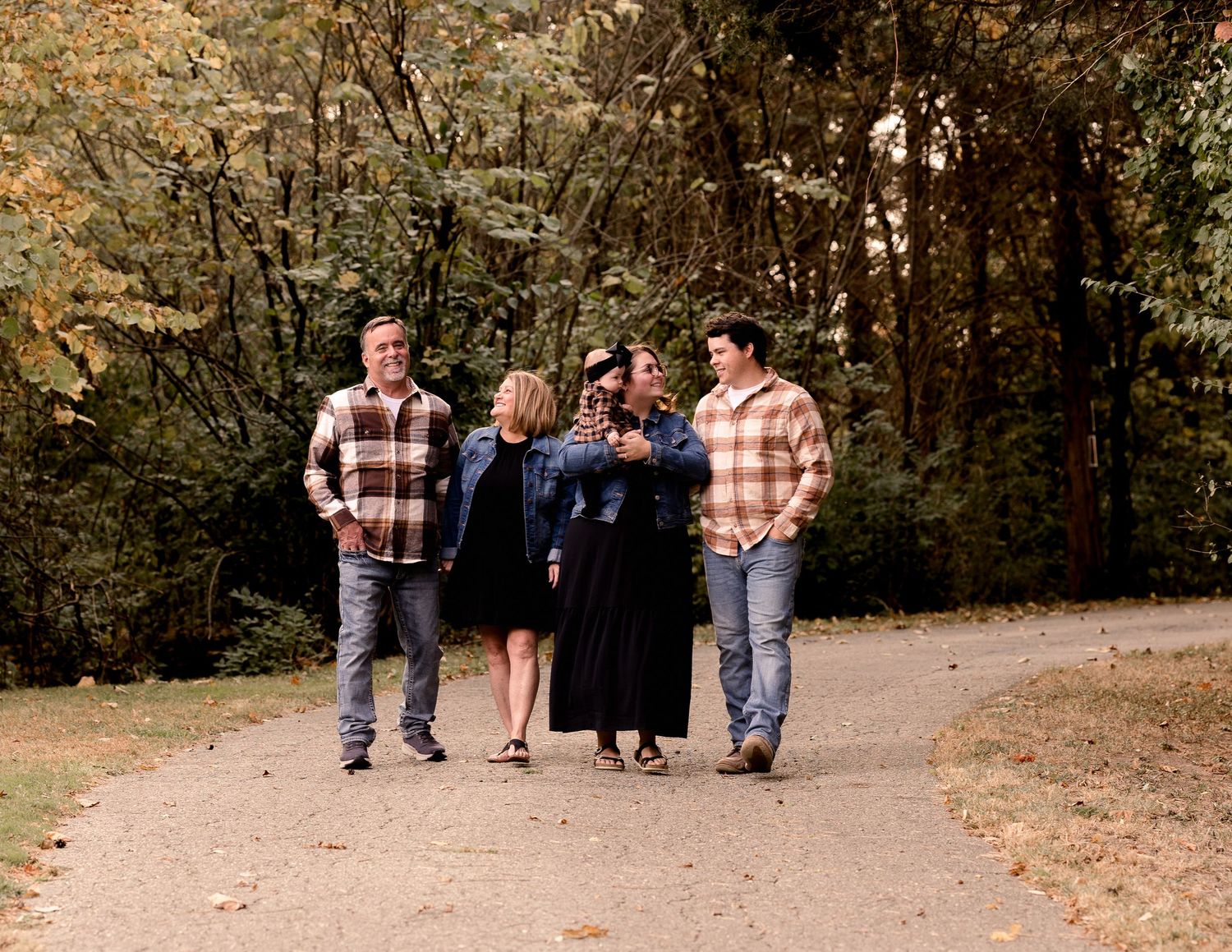 Family walking together on autumn path during outdoor photography session.