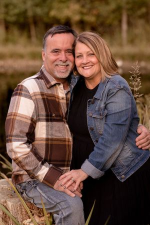 Couple in coordinating plaid and denim outfits embrace during outdoor autumn photoshoot.