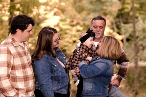Family members share candid laughing moments together during an outdoor photo session.