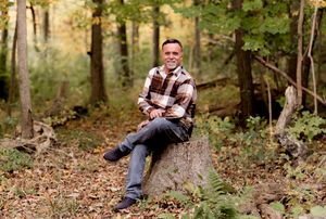 People pose for creative ground-level photos among fallen autumn leaves in a wooded setting.