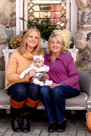 Family members sitting together on stone porch with fall decorations.