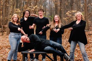Playful family photo session in autumn woods with creative pose on fallen leaves.