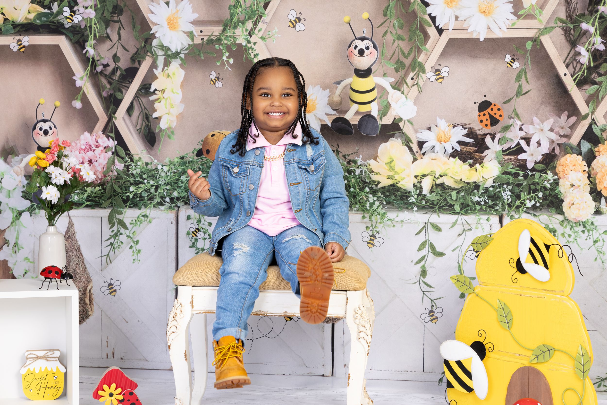Cheerful spring-themed photo setup with honeycomb backdrop, yellow bees, and floral decorations creating a garden atmosphere.
