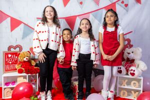 Valentine's Day themed photo setup with red and white decor, heart bunting, and festive decorations.