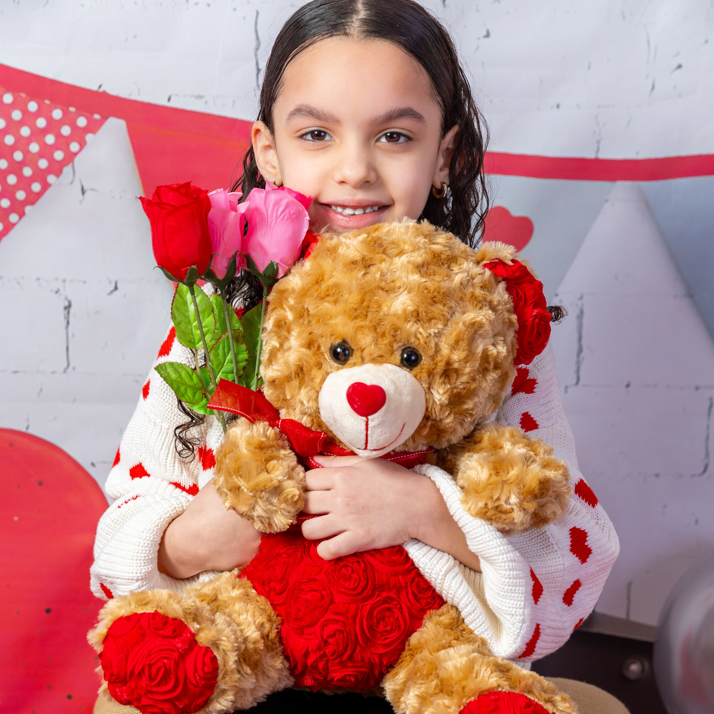 Valentine's themed portrait setting with teddy bear, red roses, and heart decorations against white backdrop.