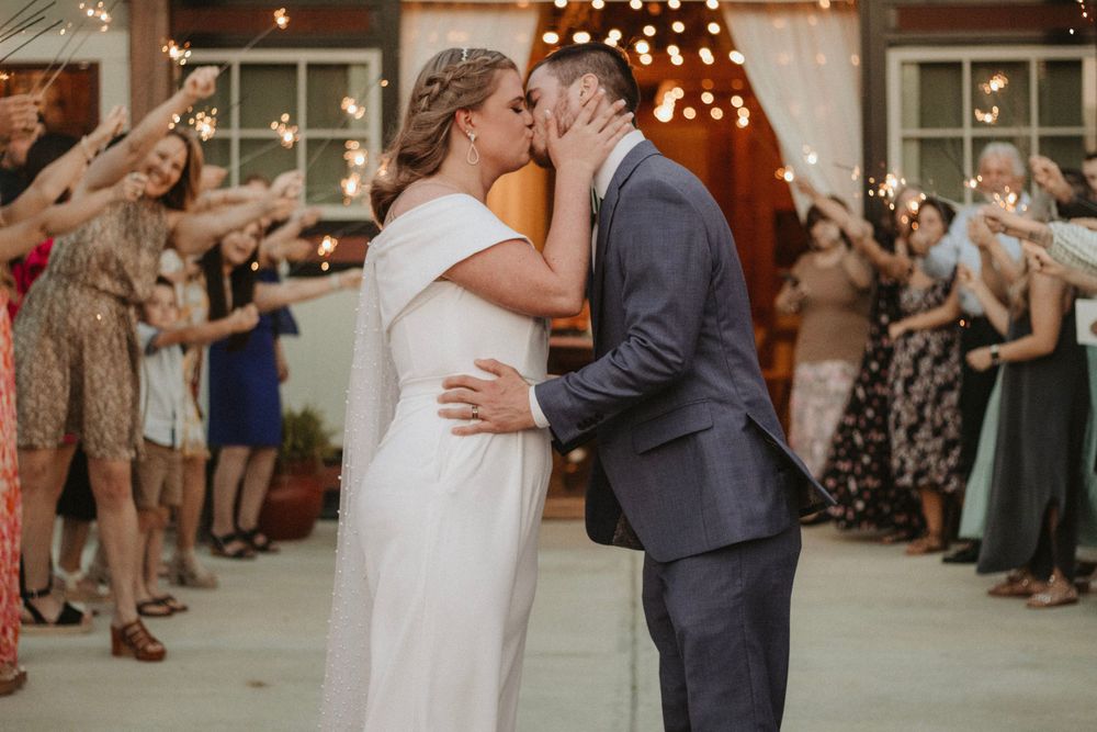 Romantic wedding dance moment under twinkling lights with guests cheering.