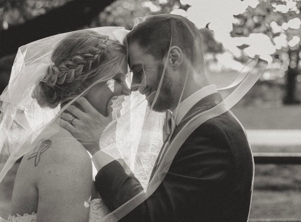 Black and white portrait of bride and groom sharing intimate moment under veil.