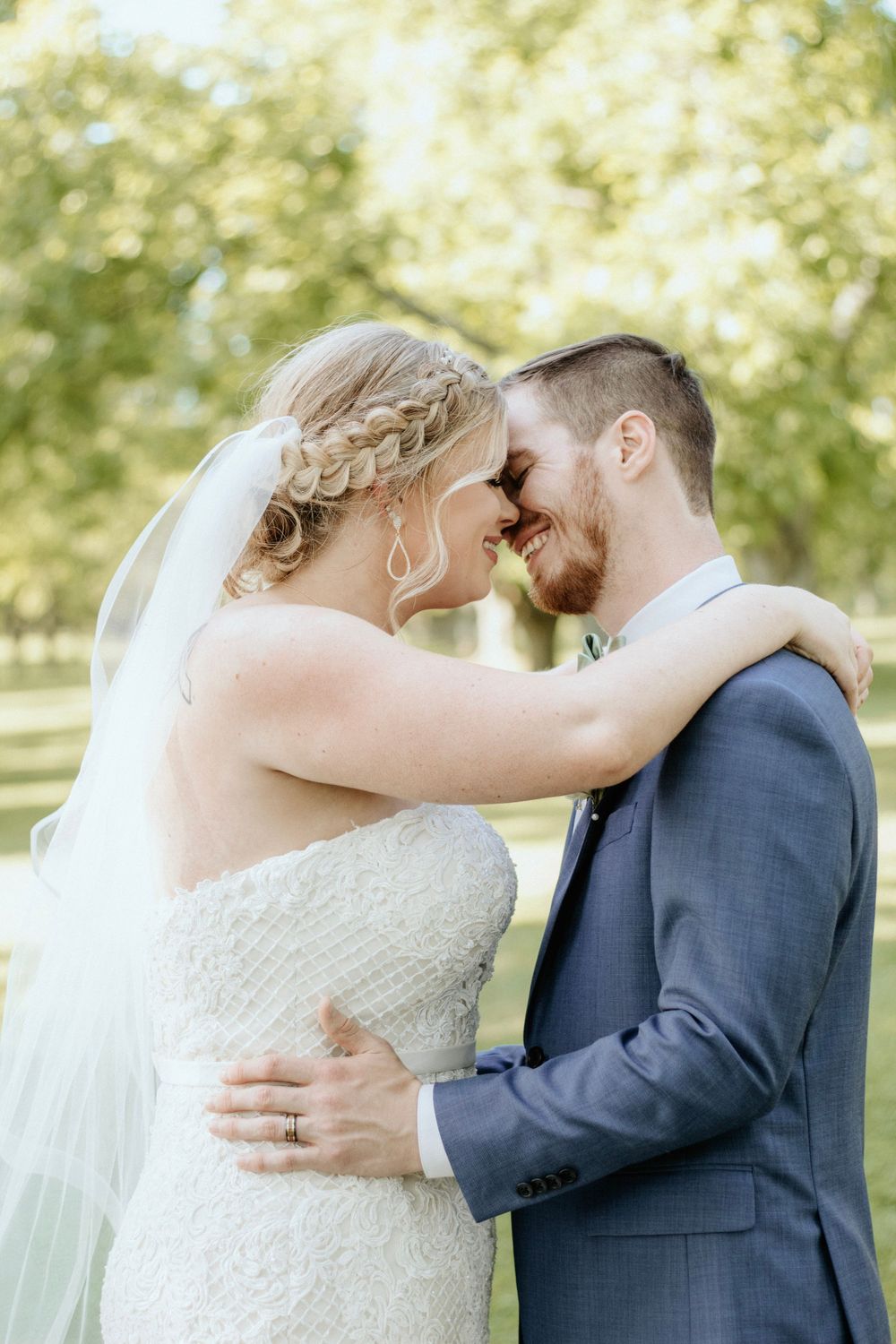 Intimate moment shared between couple in formal wedding attire with natural garden backdrop.