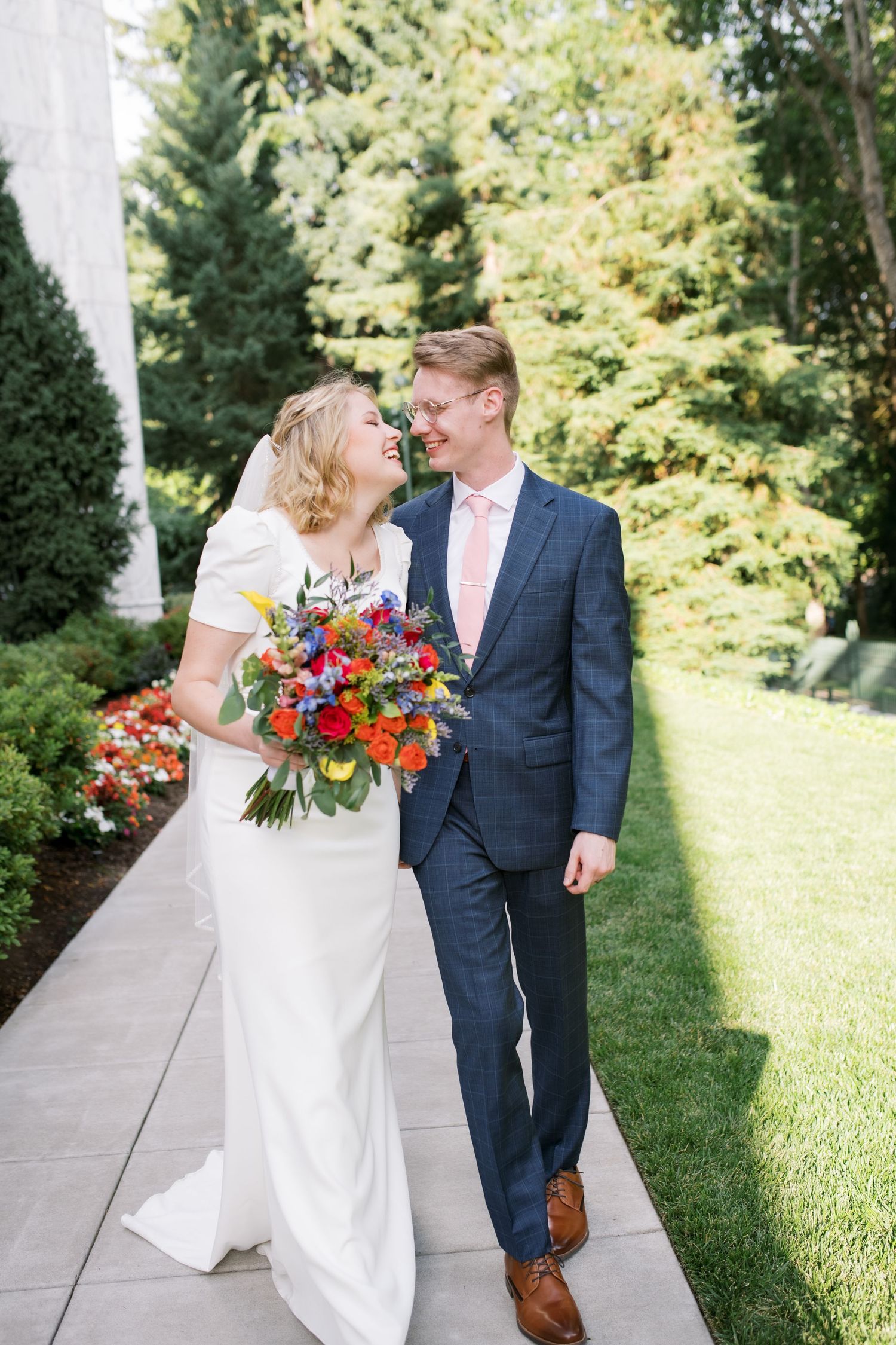 Couple walking together outdoors, bride holding vibrant wildflower bouquet.