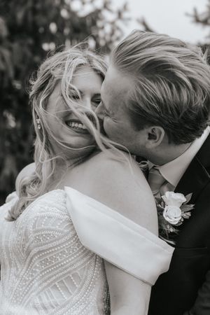 Close-up black and white wedding photo showing an intimate moment between newlyweds with romantic lighting.