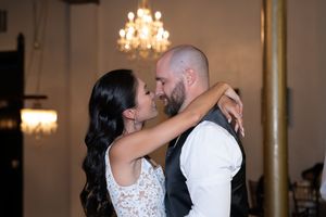 Wedding couple shares intimate first dance under elegant ballroom chandeliers.