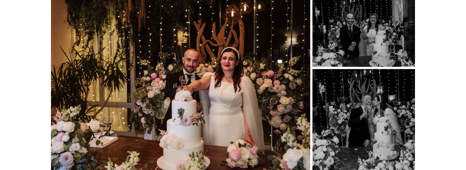 Elegant wedding reception with couple cutting tiered floral cake under warm string lights.