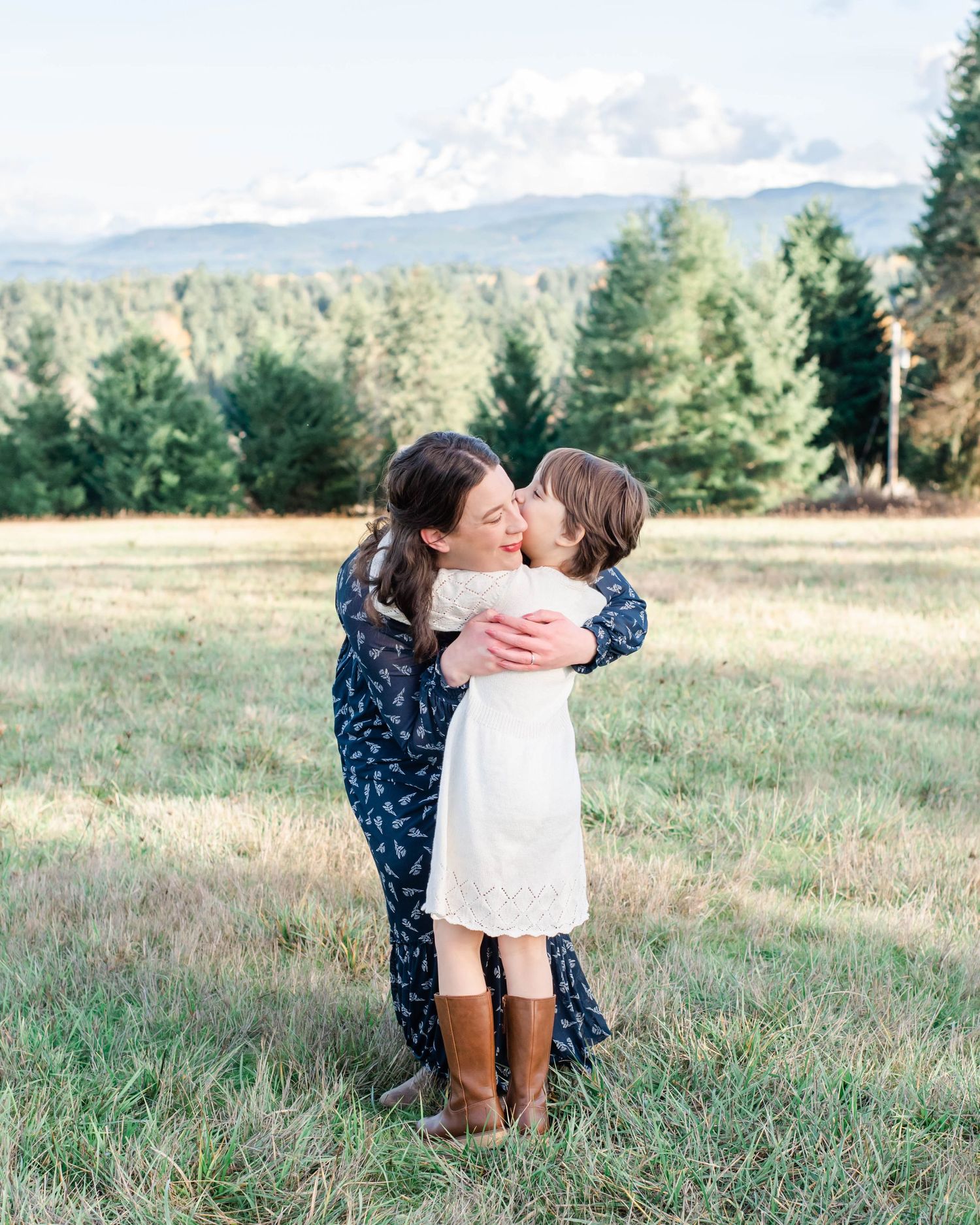 Tender embrace photographed in natural meadow setting with mountain views.