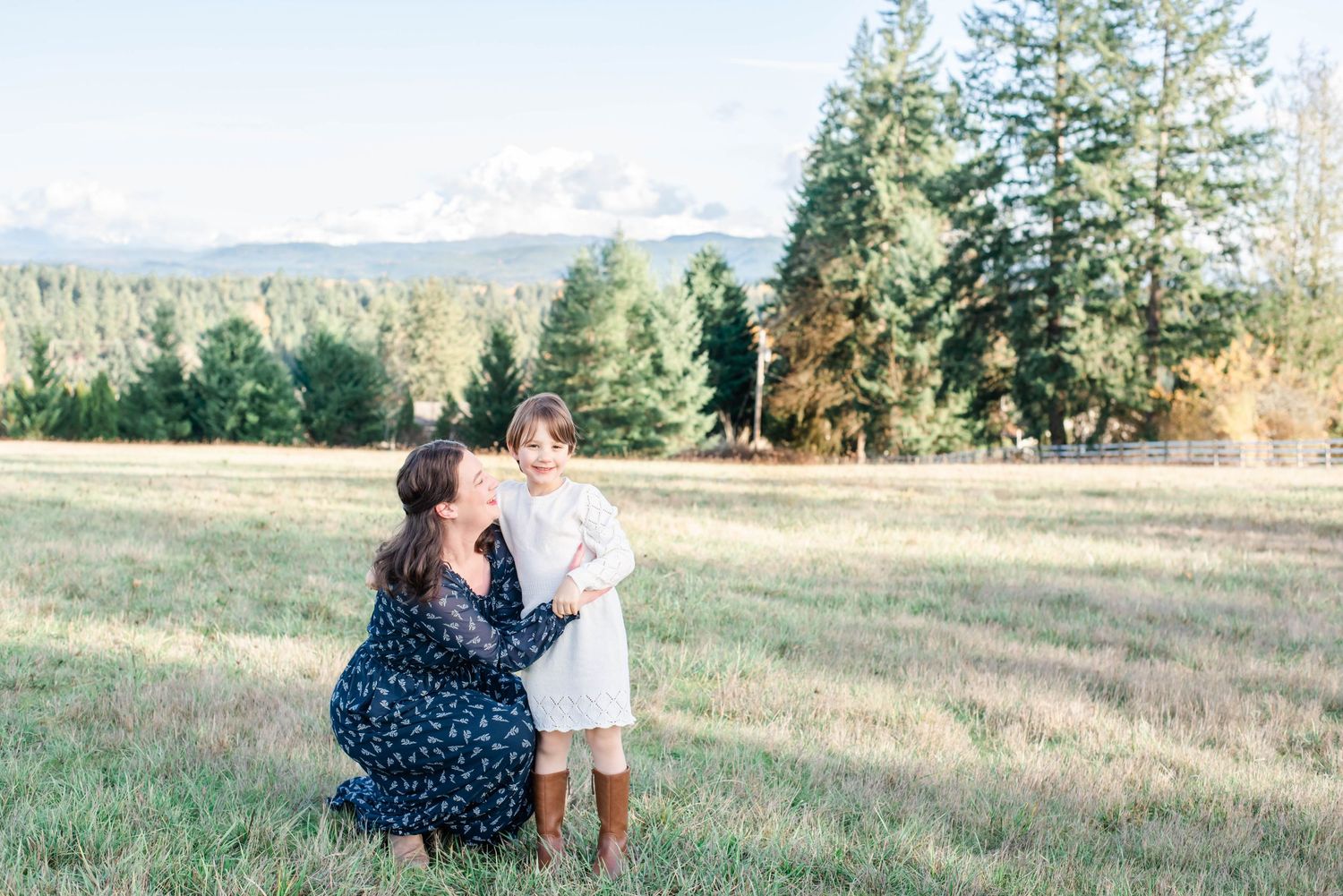 Family photoshoot in serene mountain landscape with golden lighting.