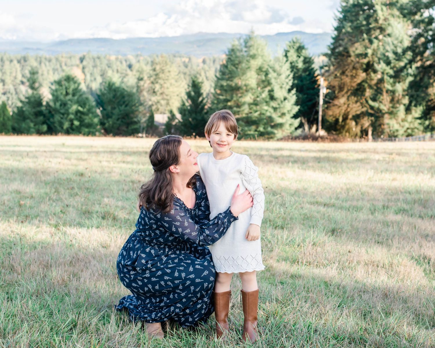 Playful family interaction in grassy field with mountain scenery.