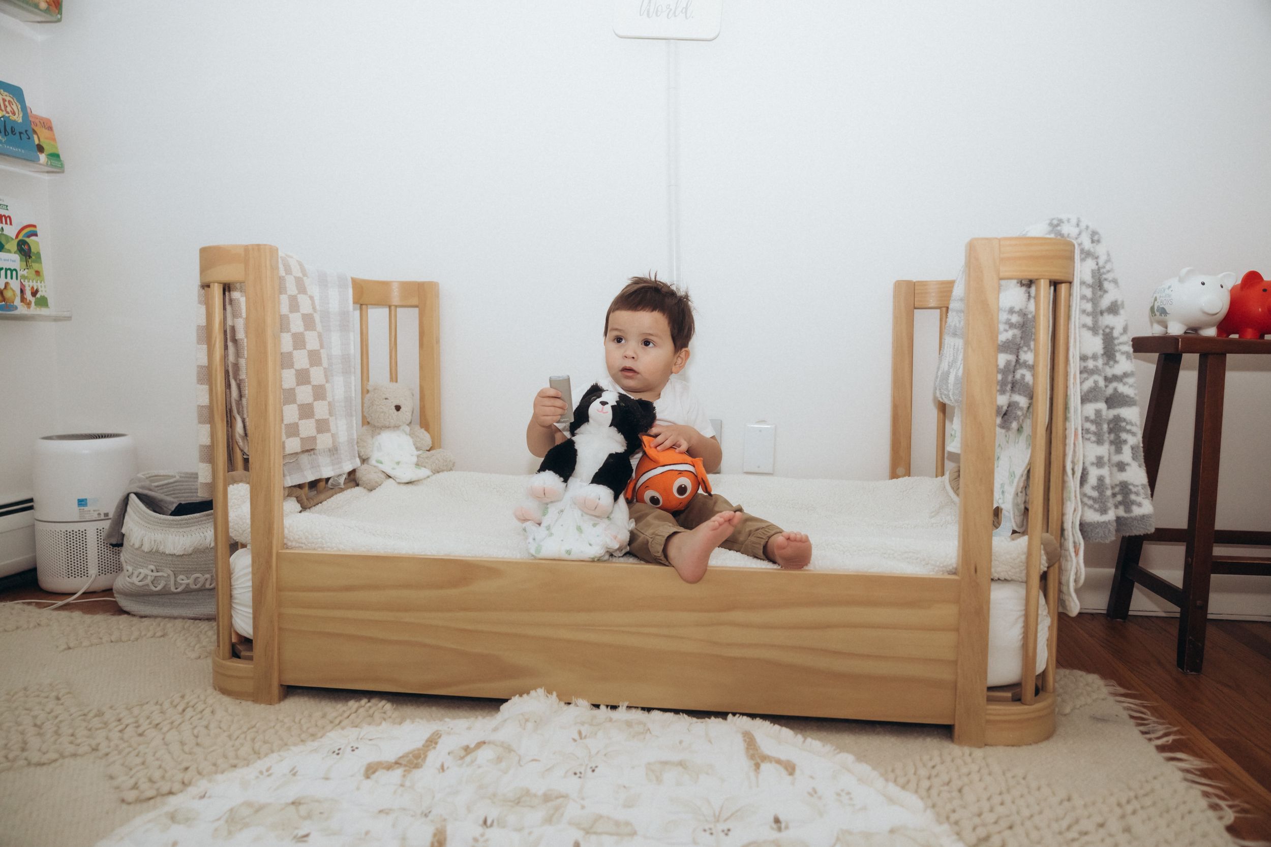 A child playing with toys in a wooden bed surrounded by scattered items.