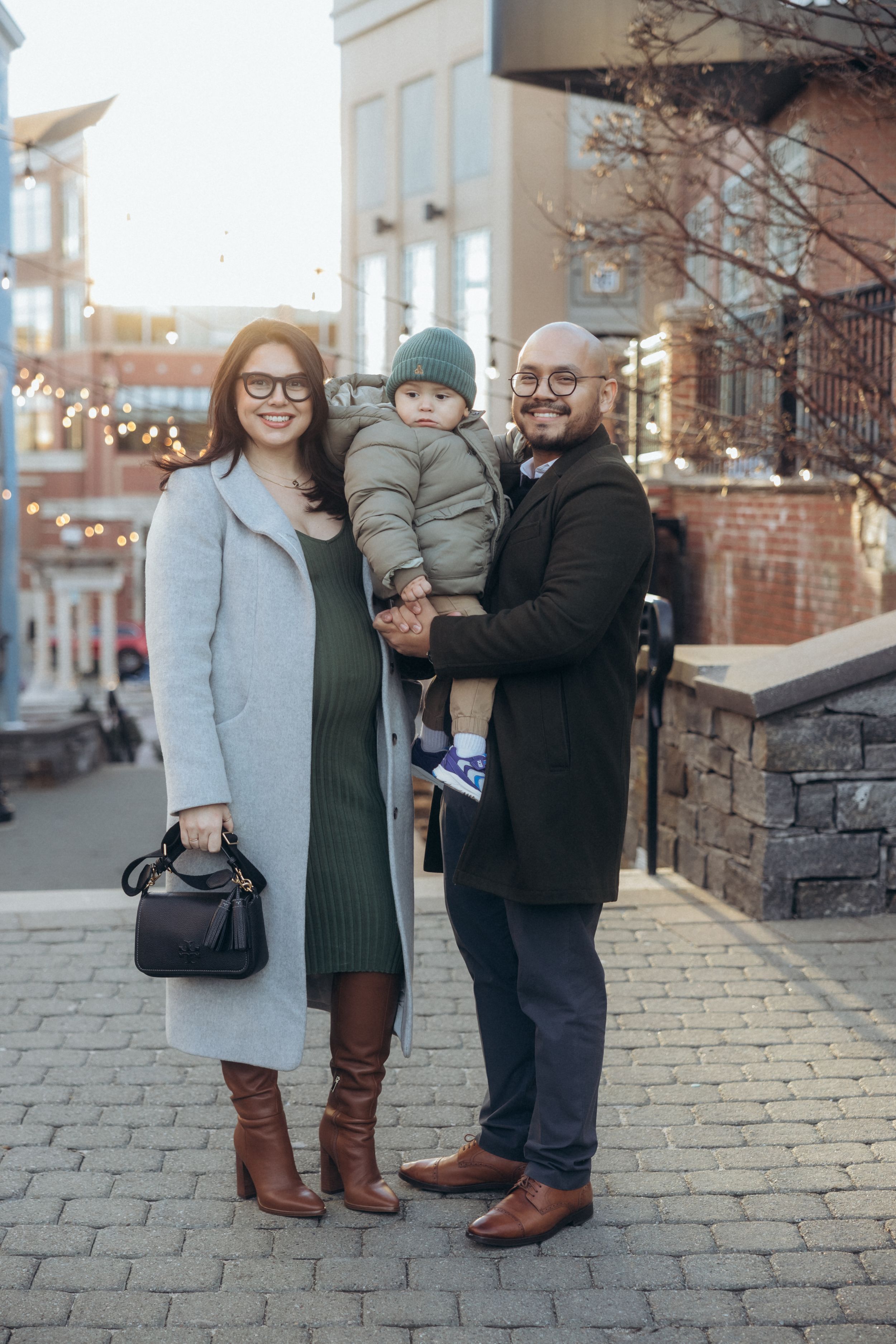 A family standing together on a brick sidewalk during winter.
