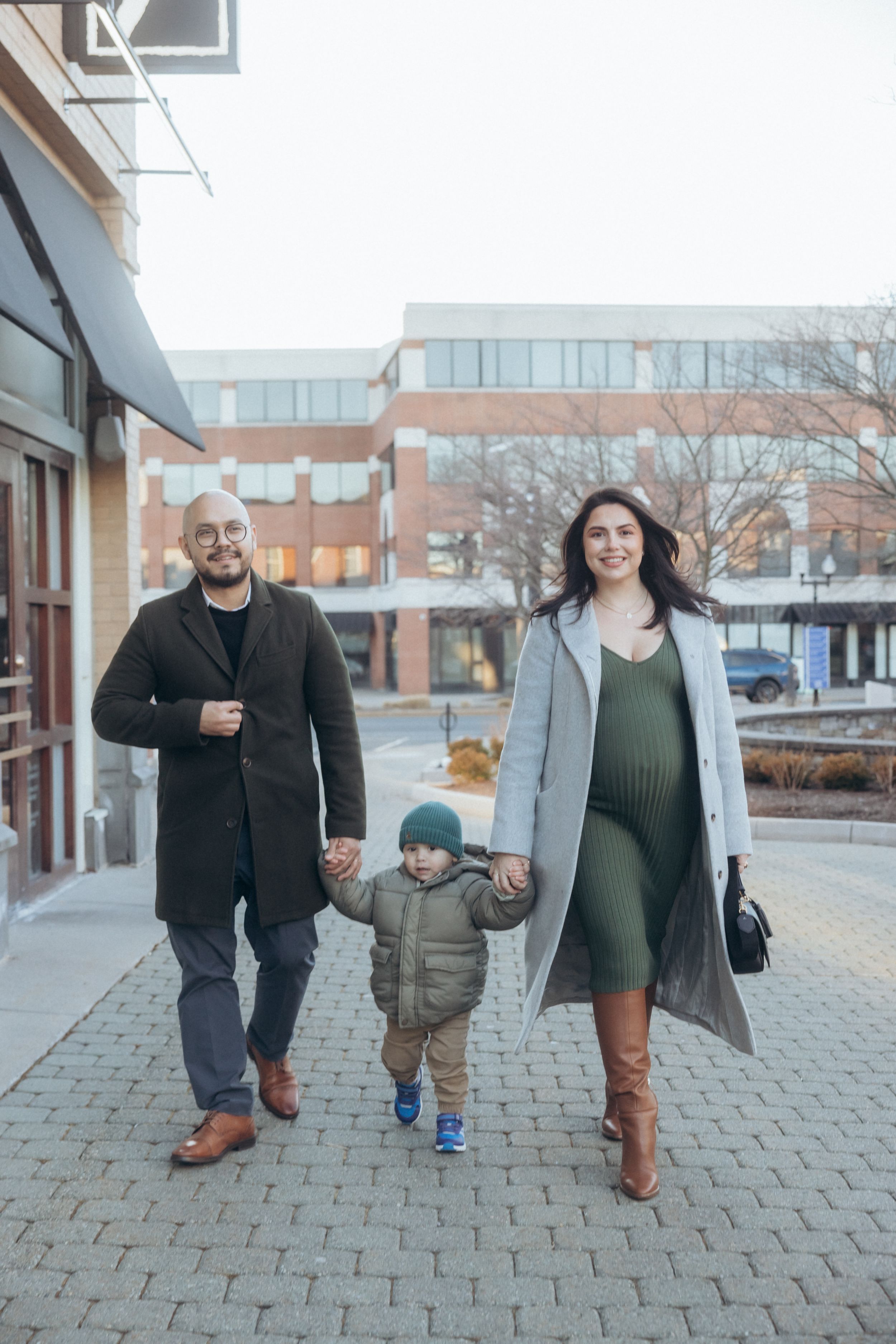 A family taking a stroll together on a paved urban sidewalk.
