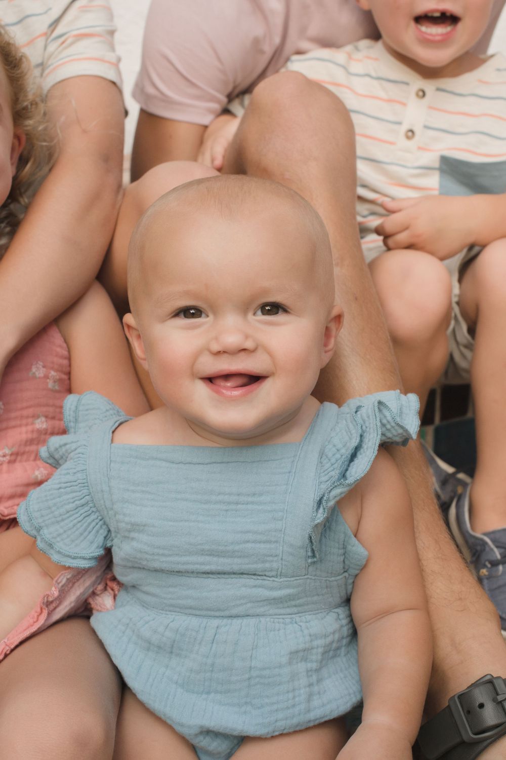 Baby wearing blue ruffled outfit smiling during portrait session.