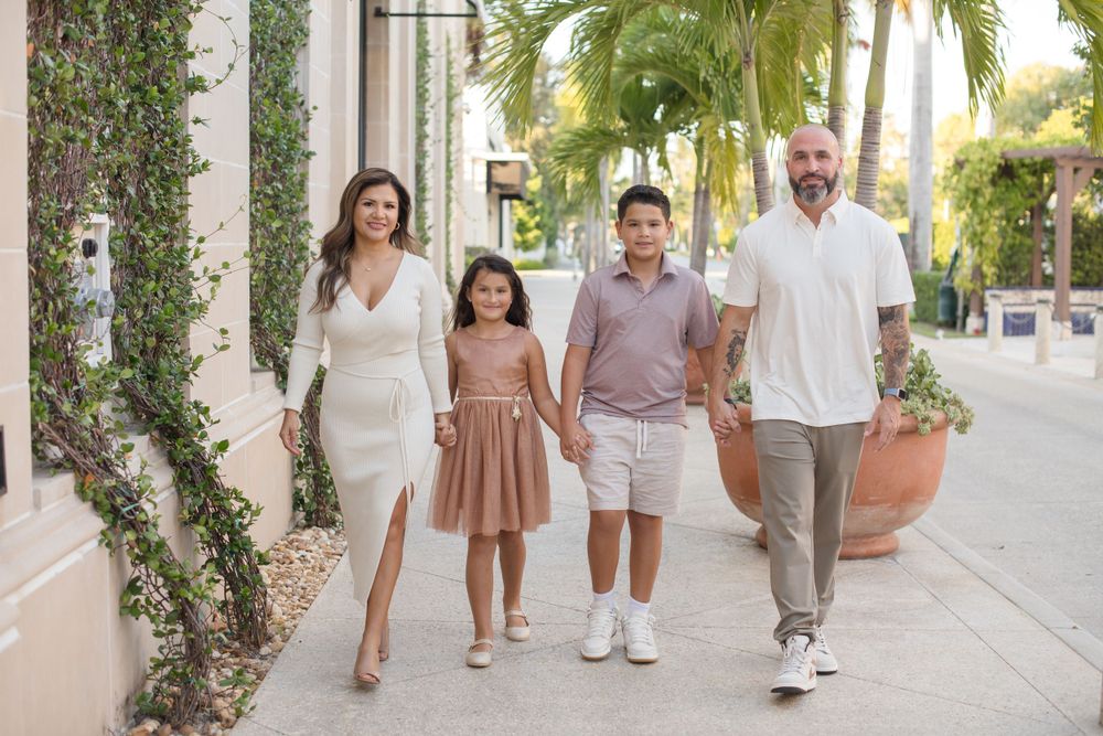 A group strolls together along a palm-lined pathway in a Mediterranean setting.