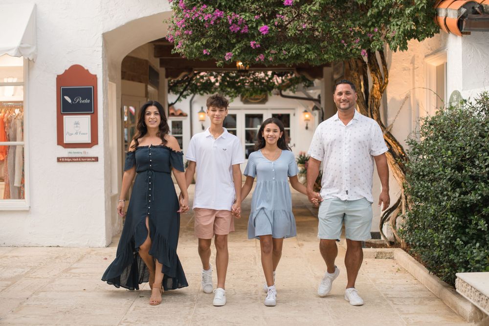 A group walks together along a Mediterranean-style courtyard pathway on a sunny day.