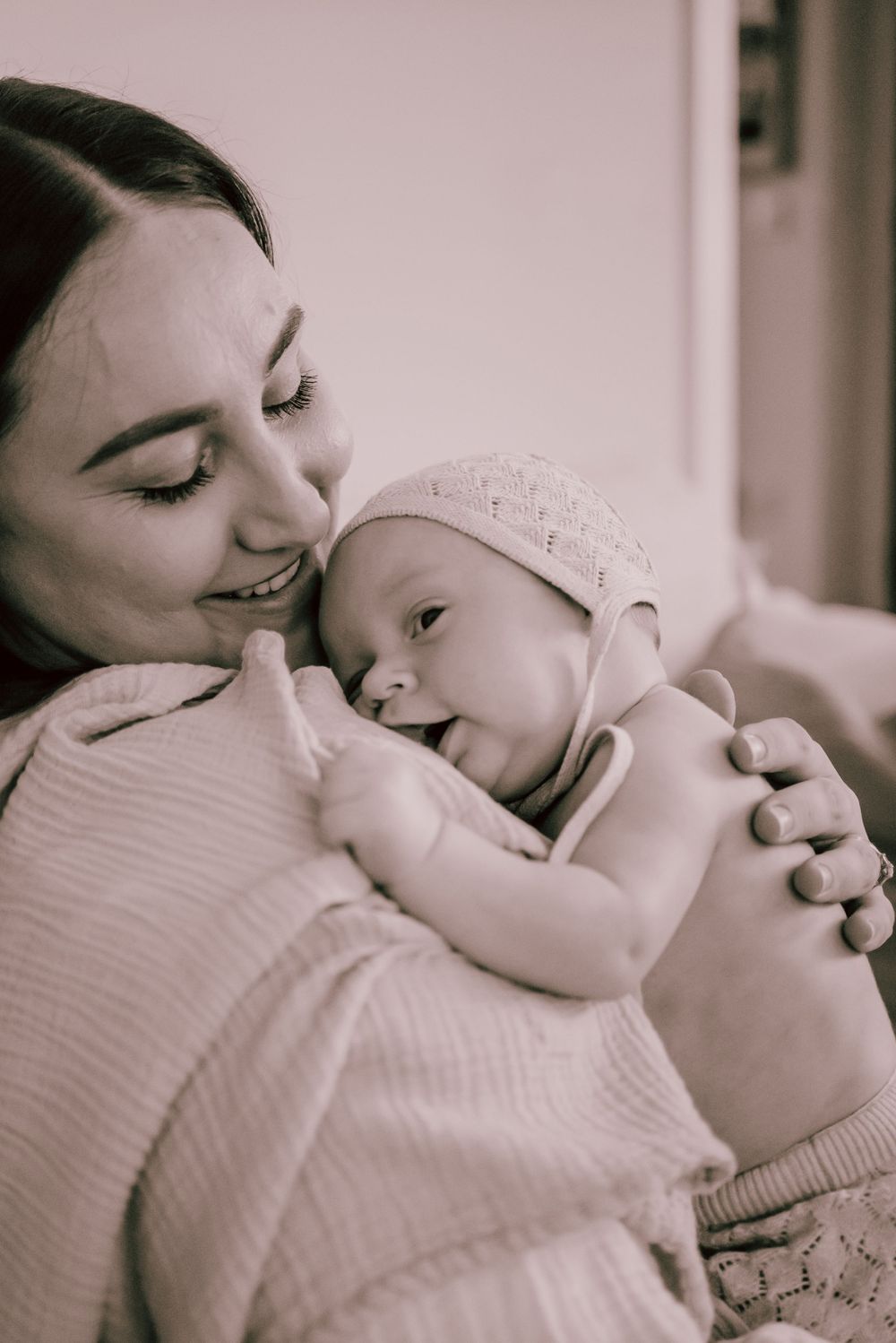 A tender black and white moment captured between mother and infant as they share a gentle embrace.