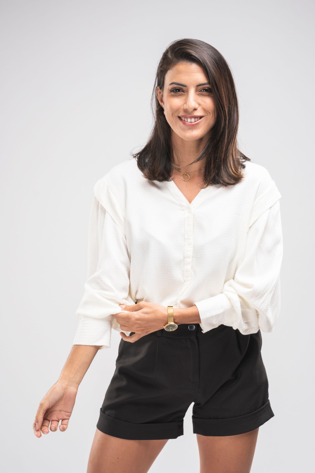 Studio portrait of a performer in casual attire posing with a microphone against white background.