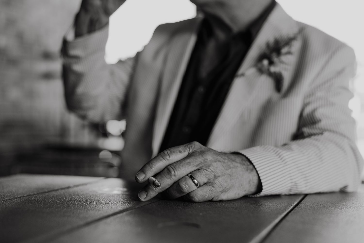 Close-up black and white photo of hands resting on a table surface.